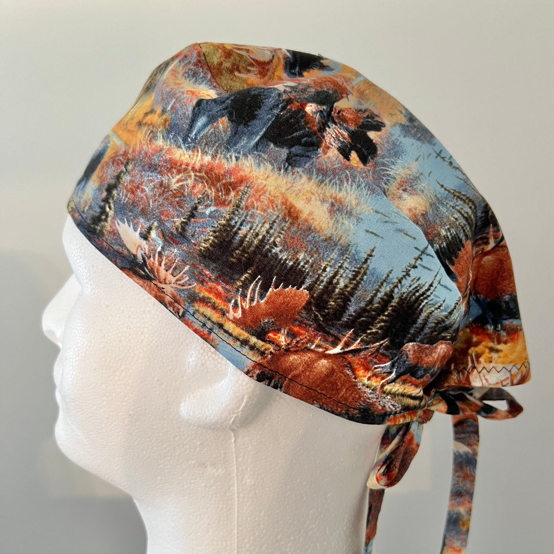Deer & moose wilderness scrub cap with pine trees and lakes on a model — handmade-in-USA men's tie-back surgical hat from OR World.