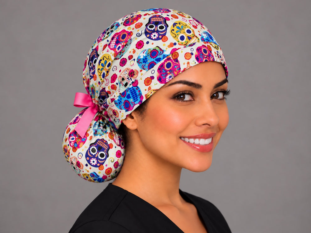 Three-quarter angle of a smiling healthcare worker in a Día de los Muertos ponytail cap, with a large violet sugar skull on the pouch at true print scale