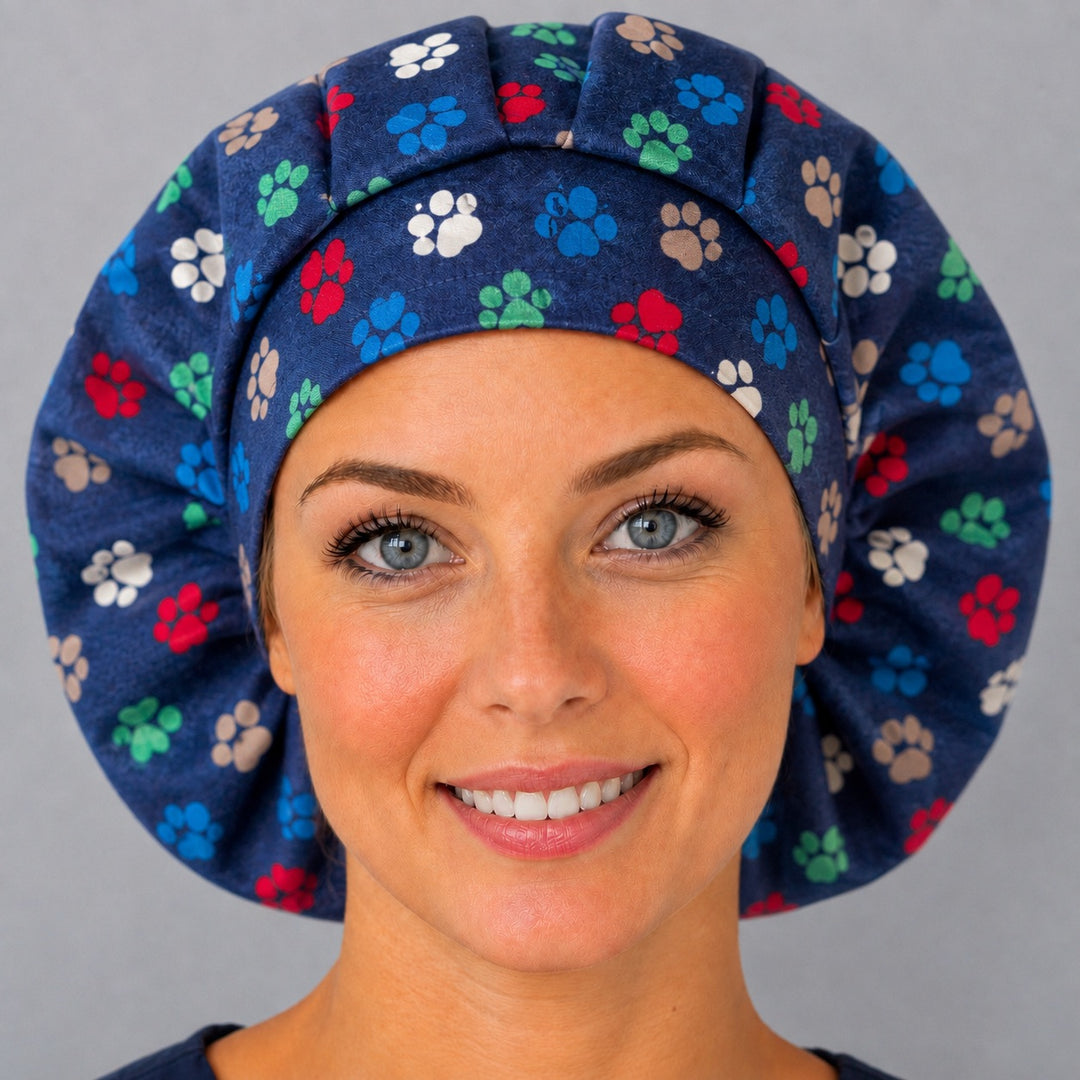 Woman wearing a dog paw print bouffant scrub cap — colorful red, blue and green paws on navy, adjustable women&