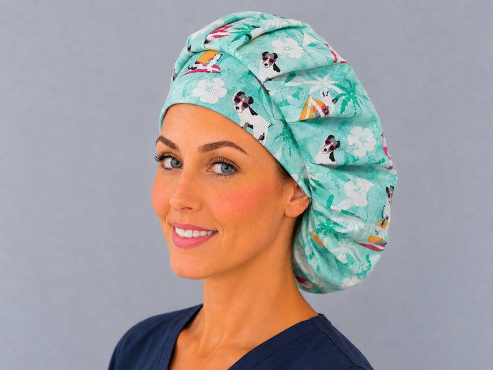 Woman wearing a dog surfing bouffant scrub cap, front view — surfing pups and palm trees on mint aqua, adjustable women&