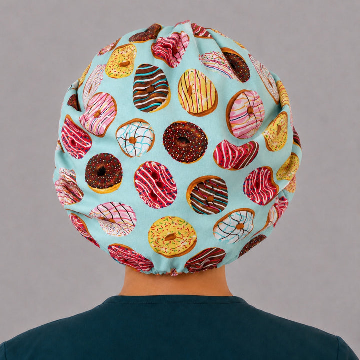 Back view of the donut print bouffant scrub cap — full roomy fit showing frosted doughnuts on aqua with elastic gather
