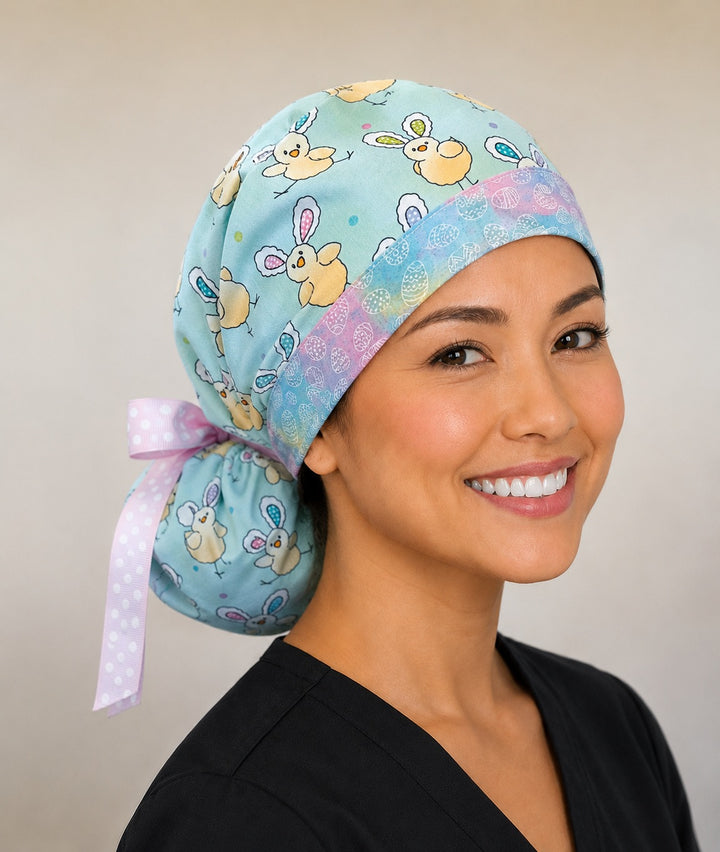 Easter chickens ponytail nurse cap left three-quarter angle on smiling model showing bunny-ear chicks, Easter eggs and pastel egg band with pink polka-dot ribbon bow
