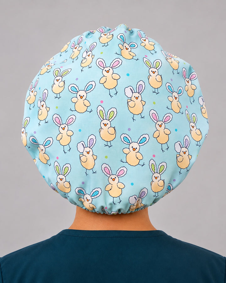 Easter chicks bouffant scrub cap with bunny ears, front three-quarter view showing pastel egg print headband