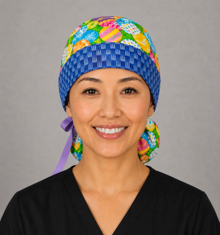 Woman wearing Easter colorful eggs ponytail scrub cap, front view smiling with vibrant decorated Easter eggs and blue bunny band with lavender ribbon tie