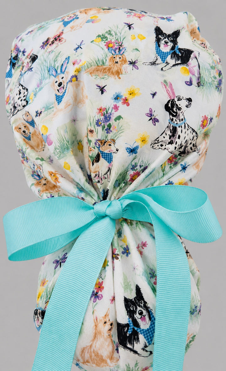 Woman wearing Easter dog ponytail scrub cap, front view smiling with bunny-ear puppies, Easter eggs and flowers with aqua band and aqua ribbon tie