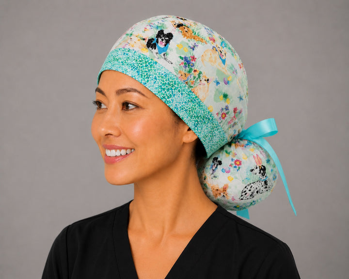 Easter dog ponytail scrub cap right three-quarter angle showing bunny-ear puppies, Easter eggs and flowers with aqua band and aqua ribbon bow