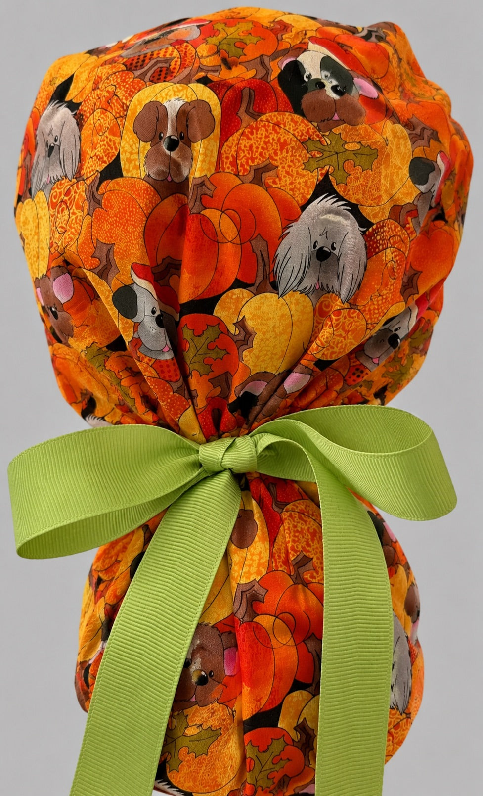 Fall dog ponytail scrub cap back view close-up showing gathered pouch full of pumpkin puppies, acorns and autumn leaves with green grosgrain ribbon bow