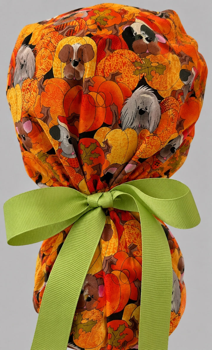 Fall dog ponytail scrub cap back view close-up showing gathered pouch full of pumpkin puppies, acorns and autumn leaves with green grosgrain ribbon bow