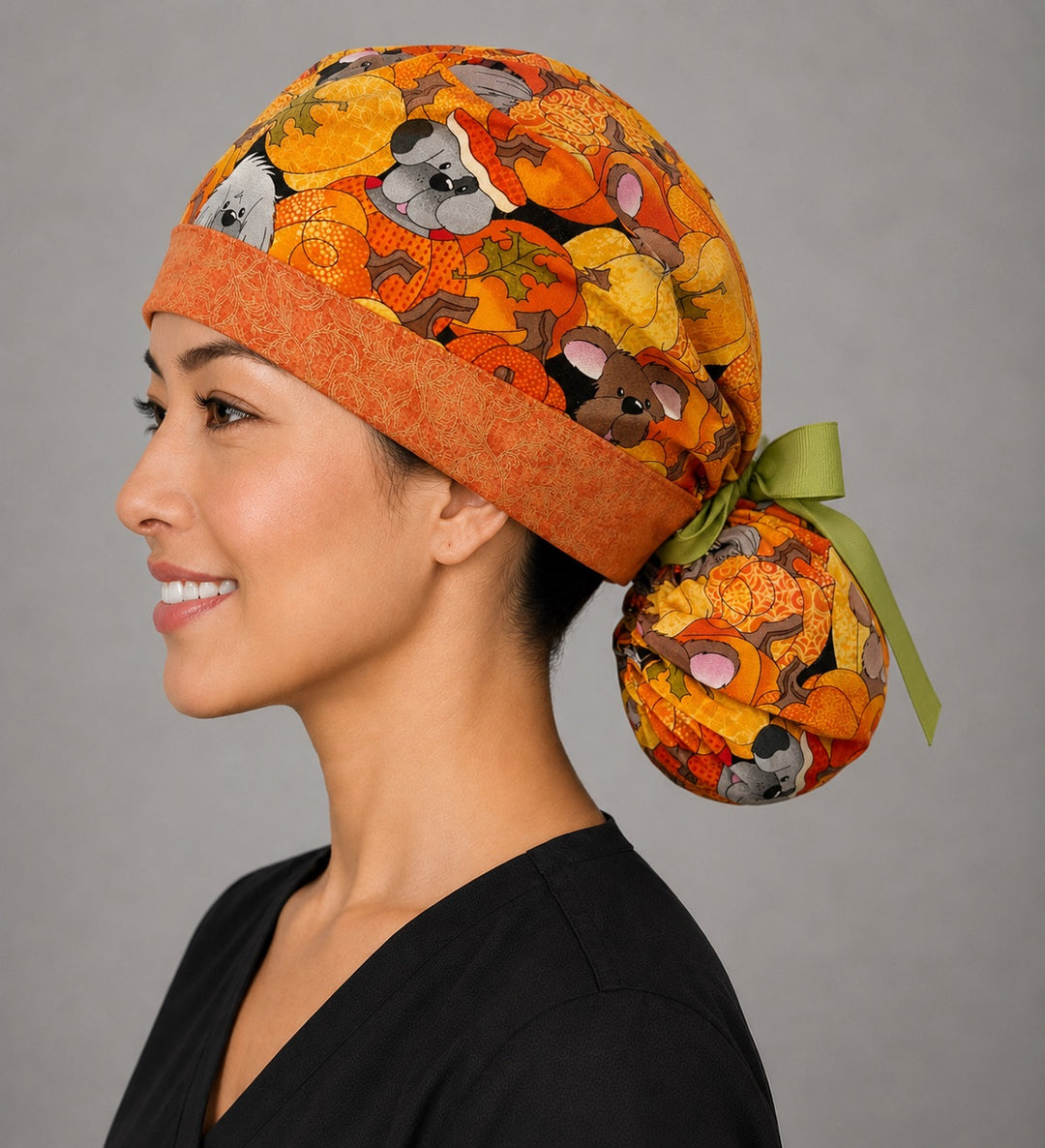 Fall dog ponytail surgical cap left side profile showing gathered ponytail pouch of pumpkin puppies and autumn leaves with orange band and green ribbon bow