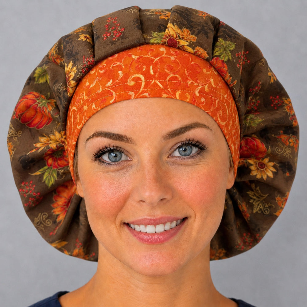 Woman wearing a fall harvest floral bouffant scrub cap, front view — pumpkins and sunflowers on brown with an orange scroll band, adjustable women's surgical hat