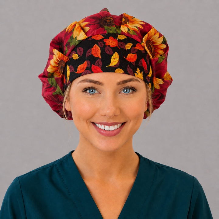 Woman wearing a fall sunflower bouffant scrub cap, front view — gold and burgundy sunflowers on black with an autumn leaf band, adjustable women&