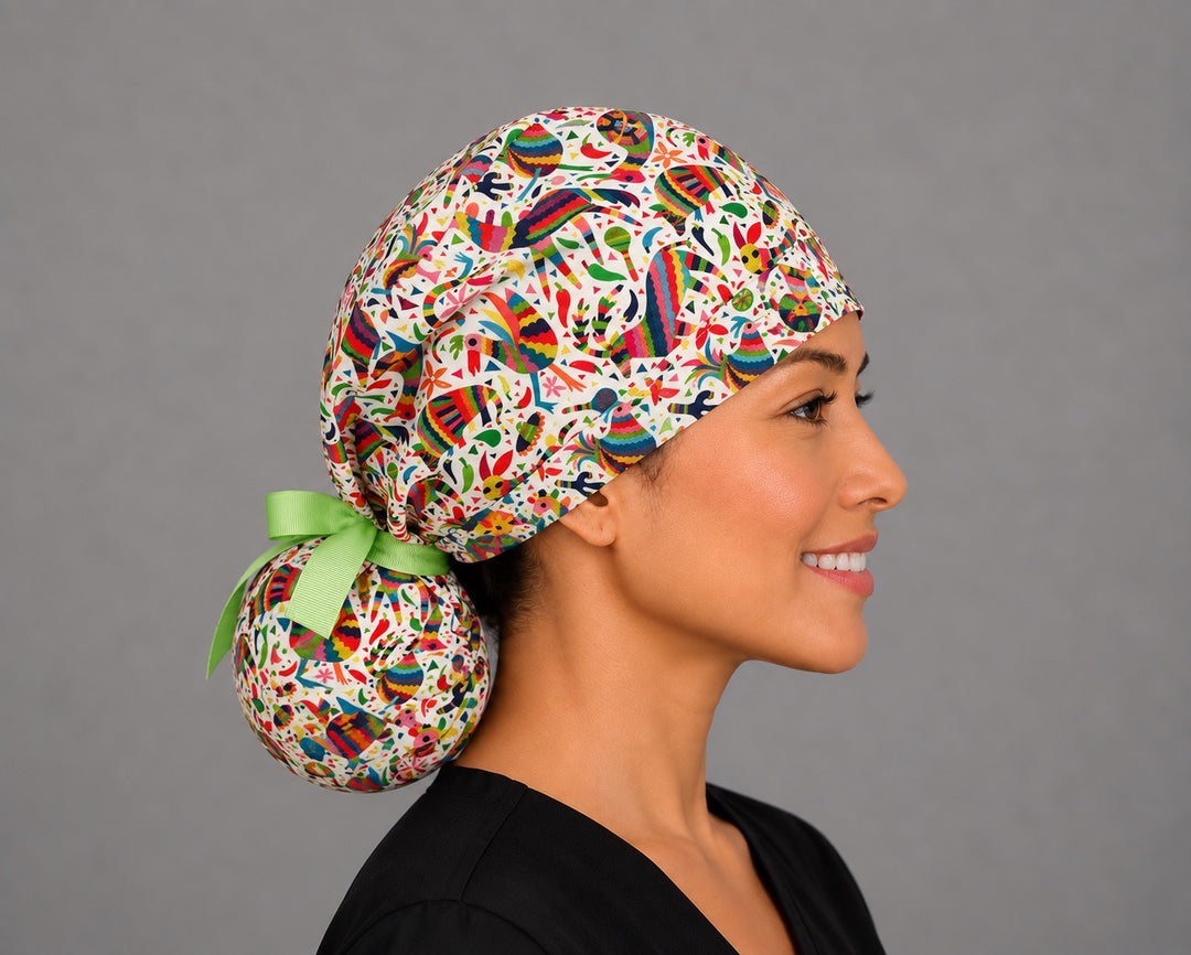 Woman wearing a fiesta piñata ponytail scrub cap, front view — colorful Mexican piñata print with lime green ribbon tie, adjustable surgical hat