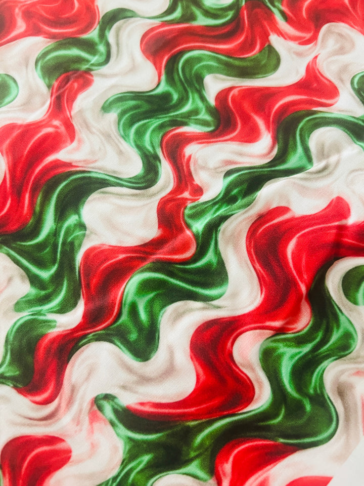 Fabric detail of the red, green and cream cotton print used on the fiesta swirl ponytail scrub cap, showing the soft glossy marbled waves
