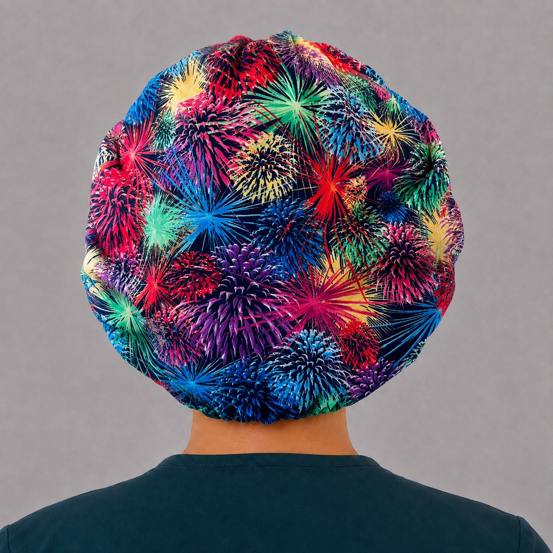 Back view of the fireworks bouffant scrub cap — full gathered fit showing neon bursts in red, purple and teal across the navy crown