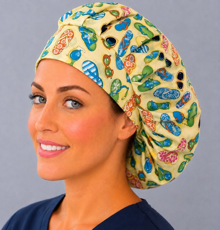 Woman wearing a tropical flip flop bouffant scrub cap, front view — colorful sandals and sunglasses on yellow, adjustable women&