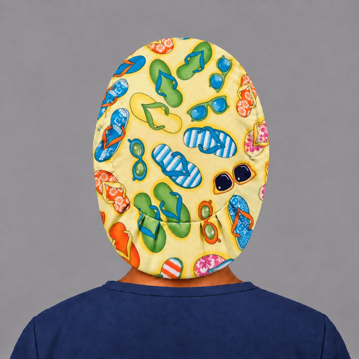 Woman wearing a Flip Flops &amp; Sunglasses Euro scrub cap, front view — colorful flip flops on sunny yellow, adjustable beach theme surgical hat