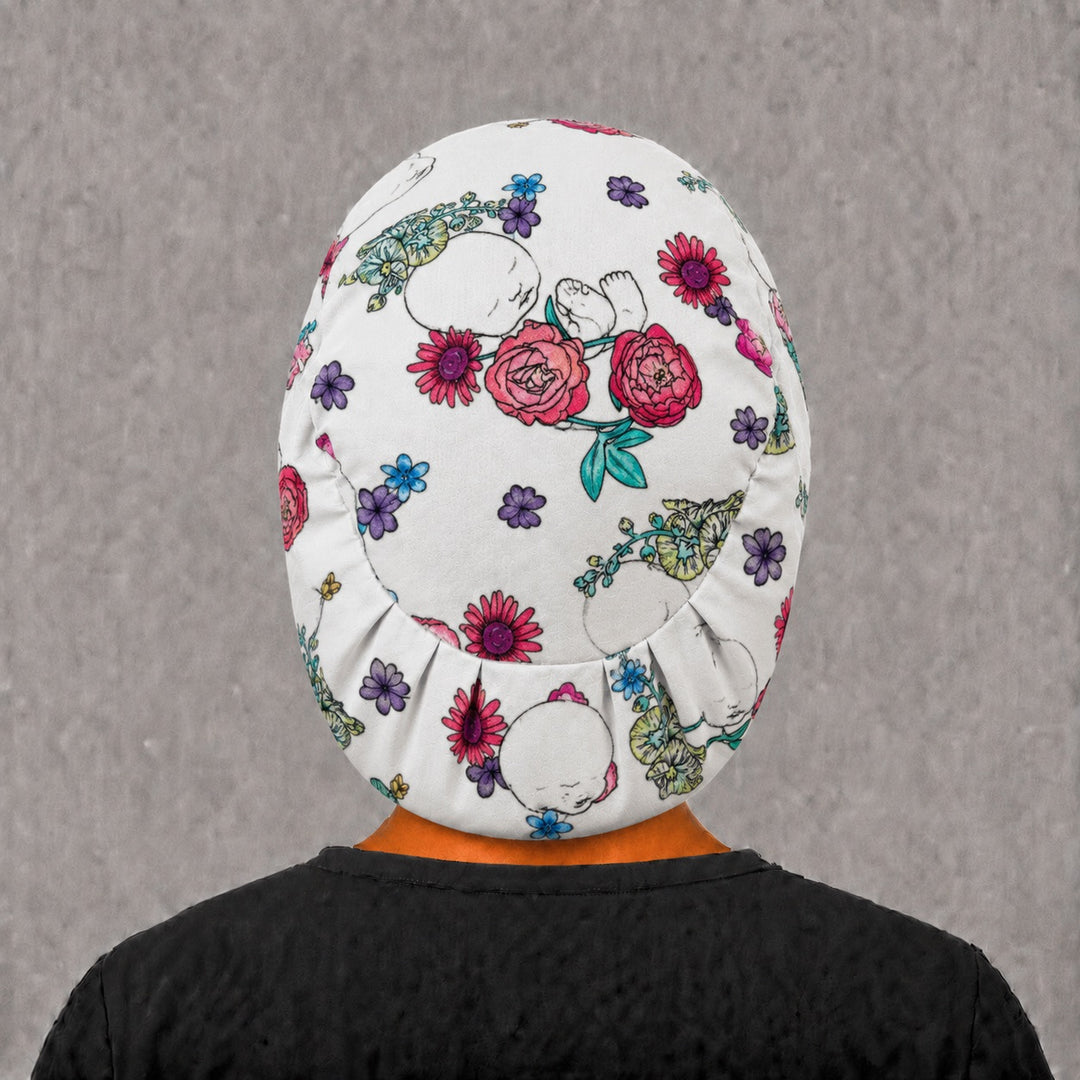 Back view of the floral baby Euro scrub cap — elastic gathered back showing newborns and florals across the cream crown