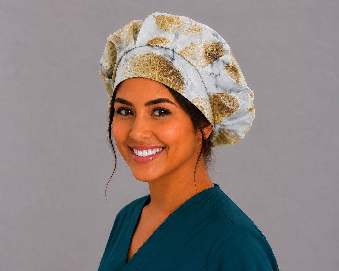 Fossil skull bone bouffant scrub cap left three-quarter angle on smiling model showing warm neutral fossil skulls on marbled stone, women's earth-tone surgical hat OR World