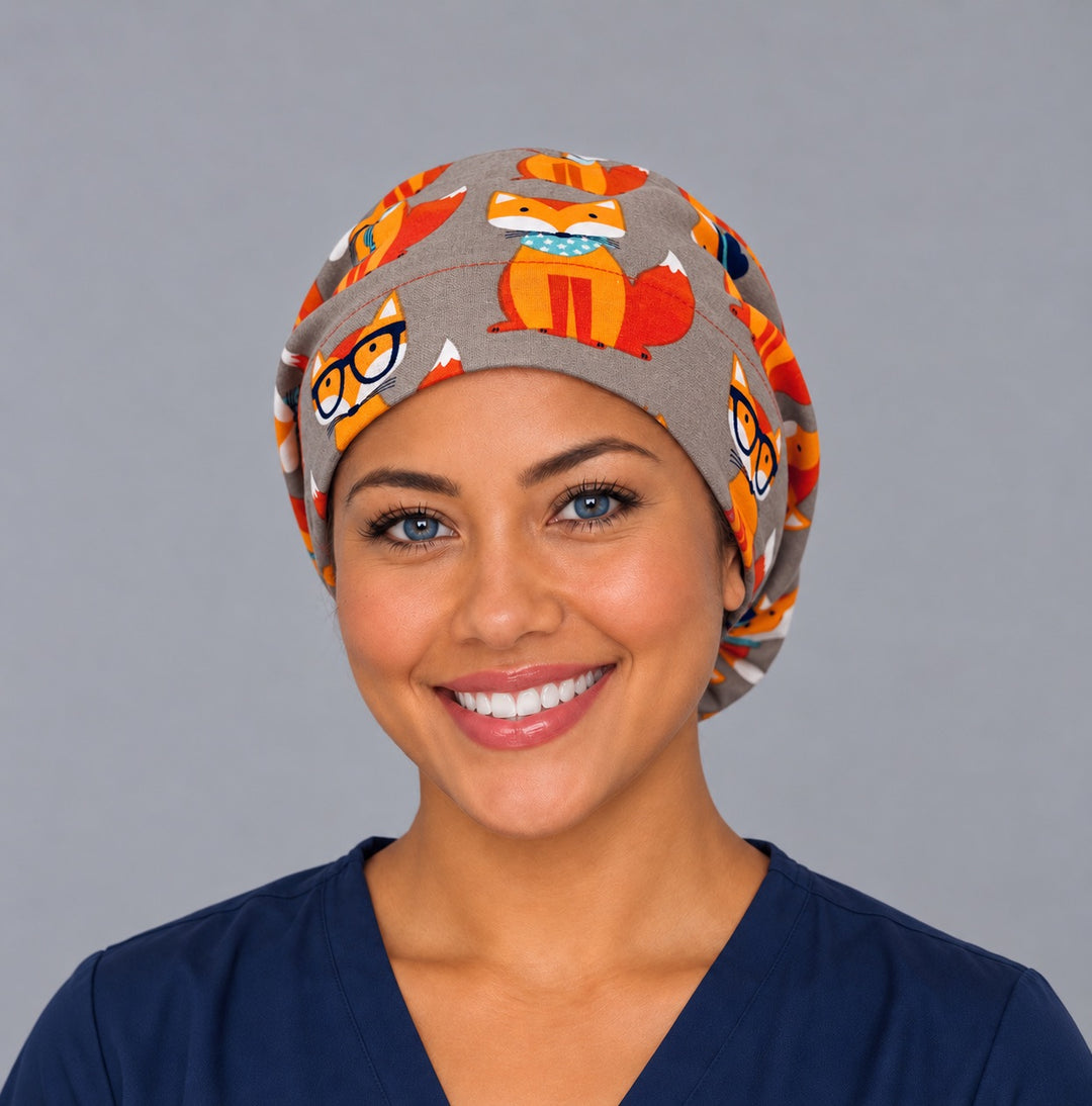Woman wearing a cute fox Euro scrub cap, front view — hipster foxes in glasses and hats on heather grey, adjustable surgical hat