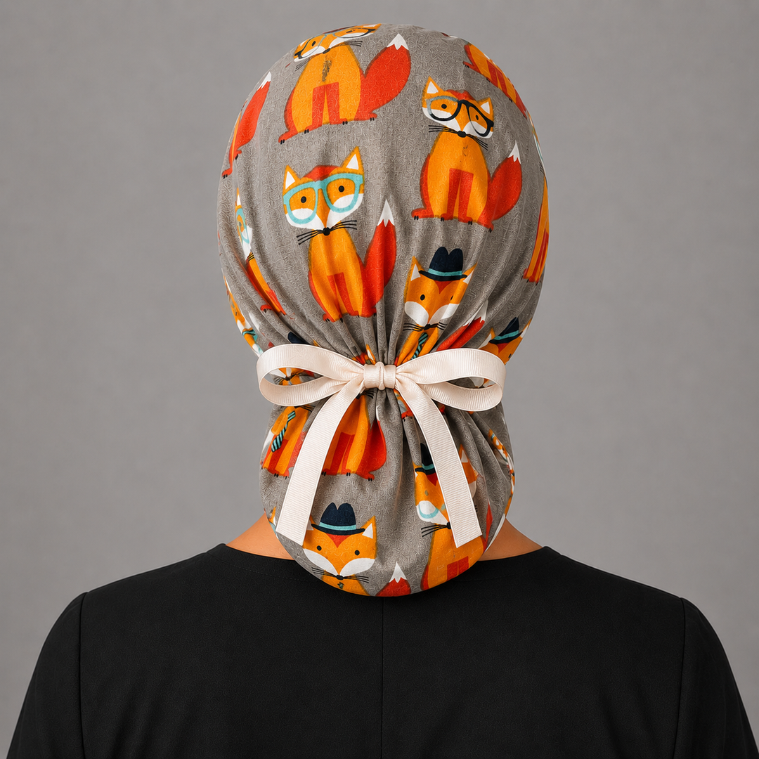 Fox print ponytail scrub cap front view on smiling model, gray and orange fox surgical hat for nurses and vet techs, handmade USA, OR World