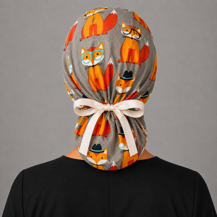 Fox print ponytail scrub cap front view on smiling model, gray and orange fox surgical hat for nurses and vet techs, handmade USA, OR World