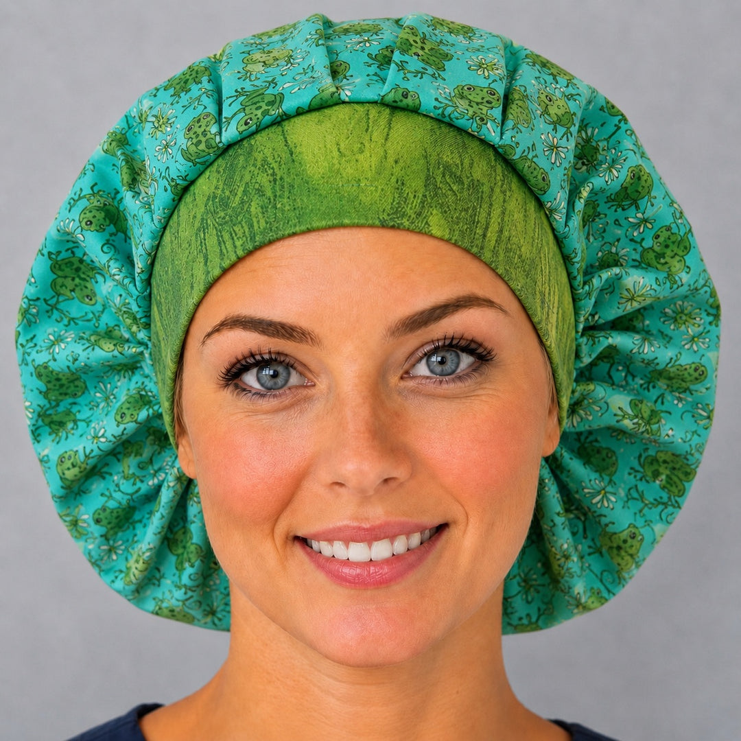 Woman wearing a cute green frog bouffant scrub cap, front view — little frogs, dragonflies and wildflowers on aqua-teal with green band, adjustable women&