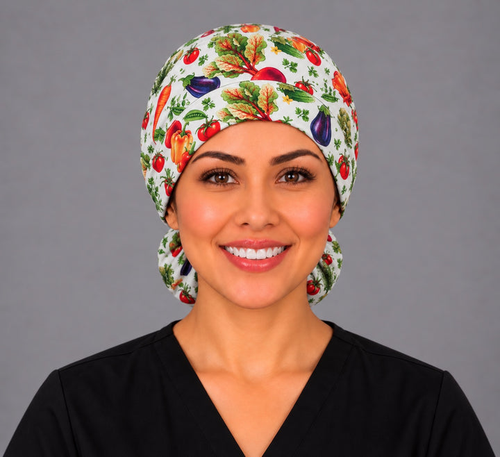 Smiling nurse in black scrubs wearing a garden vegetable ponytail scrub cap, front view with a ruby beet and leafy greens centered on the band