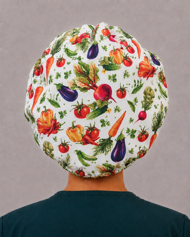 Back view of the garden veggie bouffant scrub cap — full gathered fit showing beets, carrots, radishes and herbs across the cream crown