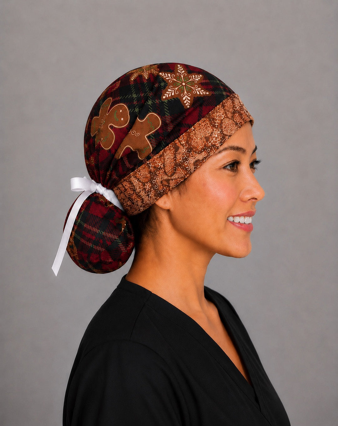 Gingerbread treats ponytail scrub cap back view close-up showing gathered pouch of red plaid, gingerbread men and star cookies with white grosgrain ribbon bow