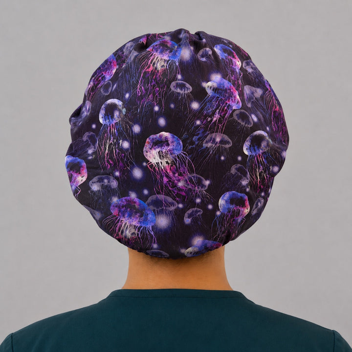 Back view of the glow jellyfish bouffant scrub cap — full roomy fit with neon jellyfish drifting across a deep underwater ocean print