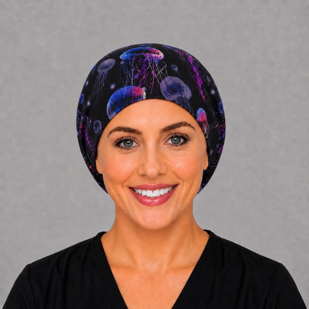 Woman wearing a glow jellyfish Euro scrub cap, front view — neon pink and blue jellyfish on black, adjustable women's surgical hat