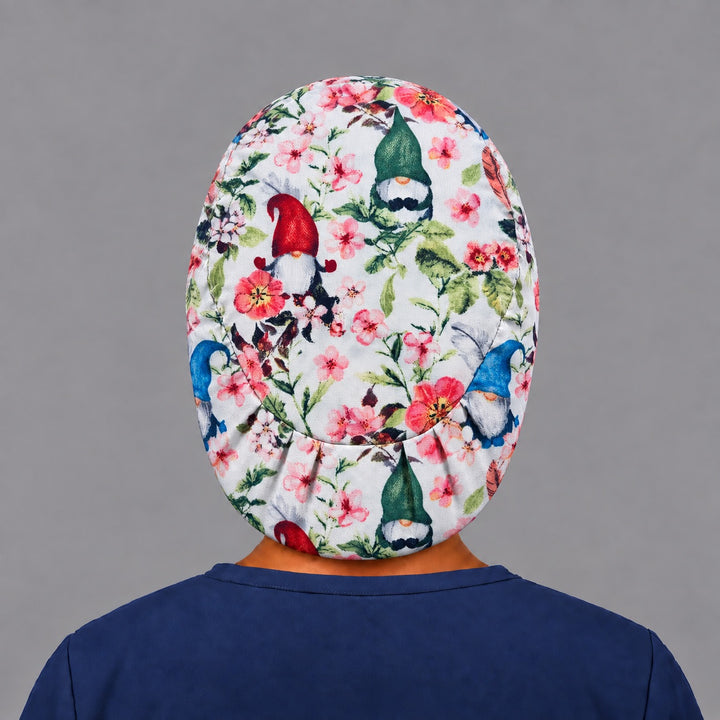 Back view of the gnome floral Euro scrub cap — elastic gathered back showing gnomes and blossoms across the white crown