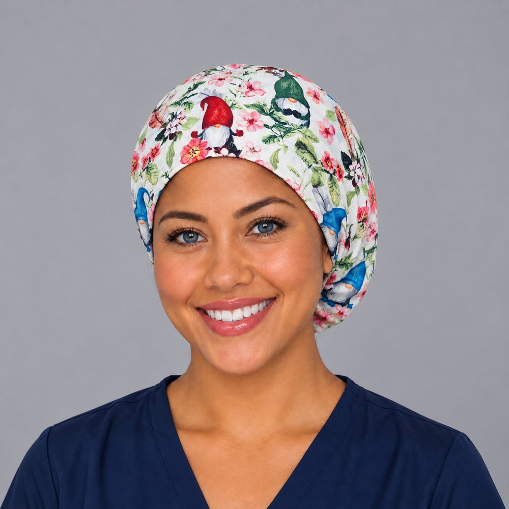 Woman wearing a spring gnome floral Euro scrub cap, front view — garden gnomes and pink blossoms on white, adjustable surgical hat