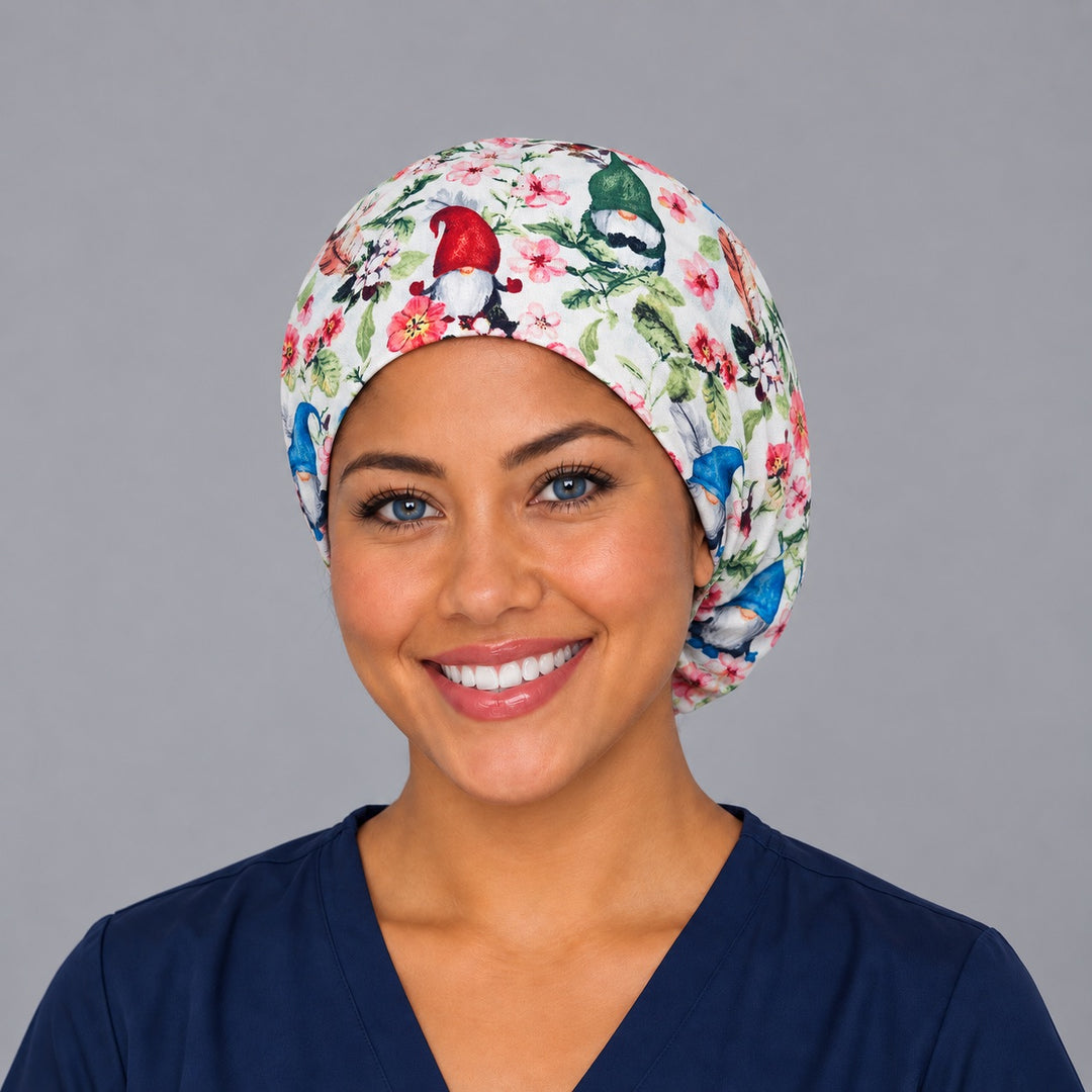 Woman wearing a spring gnome floral Euro scrub cap, front view — garden gnomes and pink blossoms on white, adjustable surgical hat