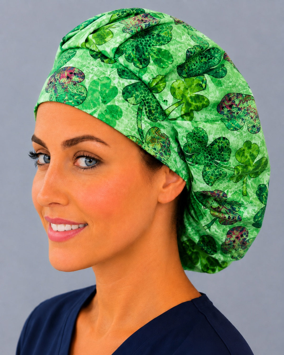 Green Irish clover bouffant scrub cap, left angled smiling view — magenta-accented shamrock print for OR nurses and surgical techs