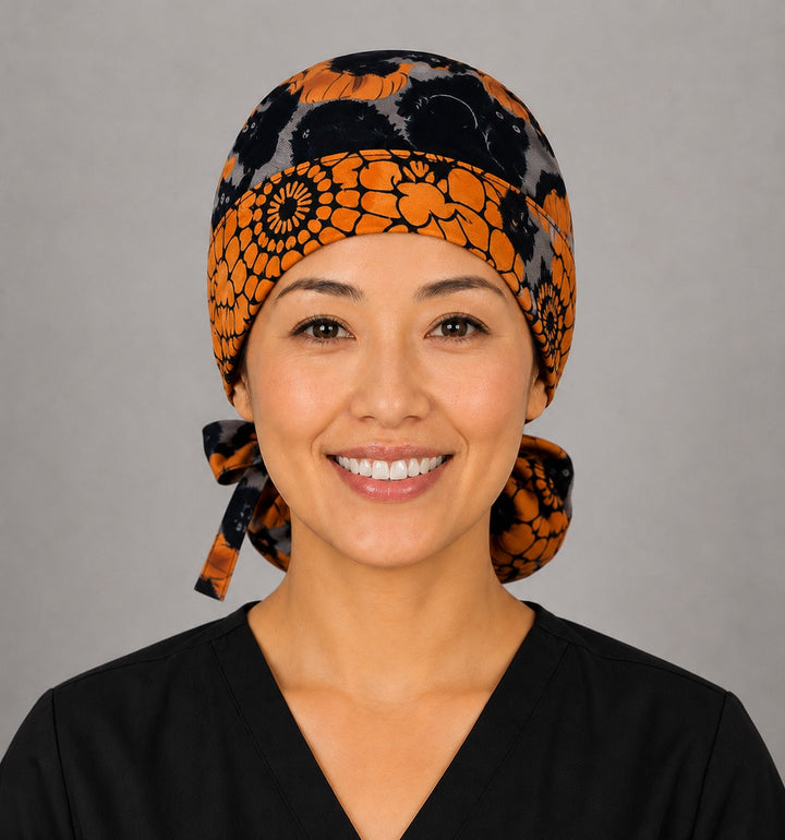 Halloween black cat and pumpkin ponytail scrub cap back view close-up showing gathered pouch full of fuzzy black cats and orange pumpkins on gray with orange ribbon bow