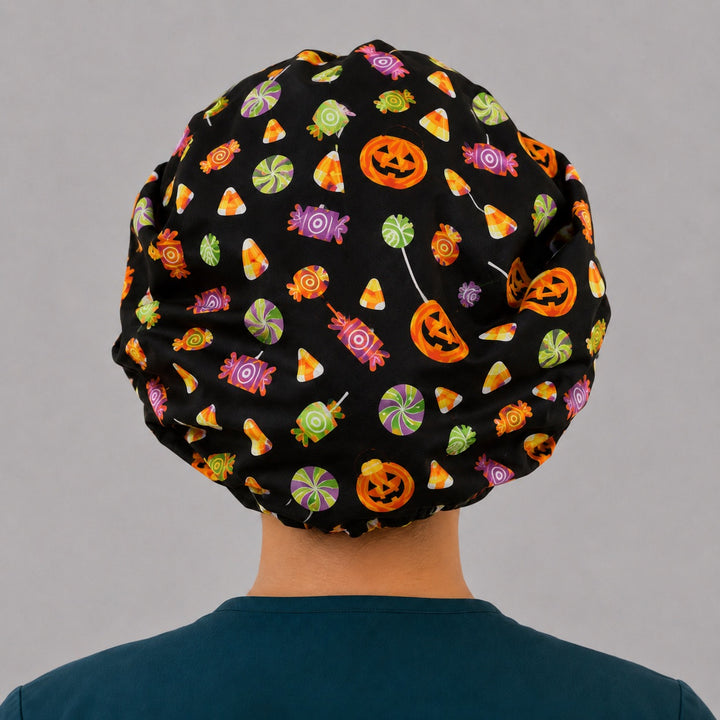 Halloween candy and pumpkin bouffant scrub cap back view showing full candy corn, lollipop and jack-o-lantern print on black, OR World surgical hat