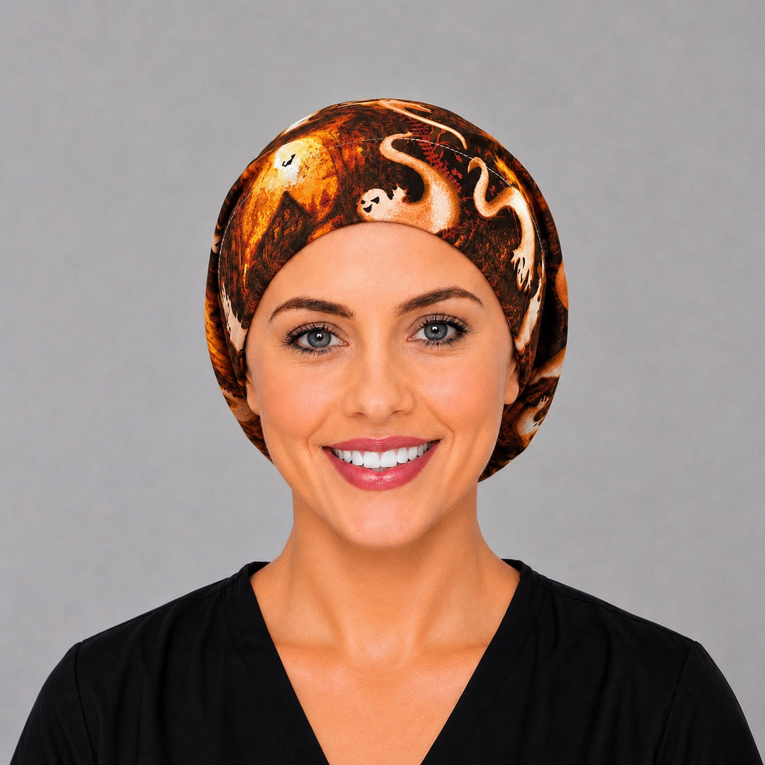 Woman wearing a Halloween ghost Euro scrub cap, front view — white ghosts and glowing harvest moons on black and orange, adjustable surgical hat