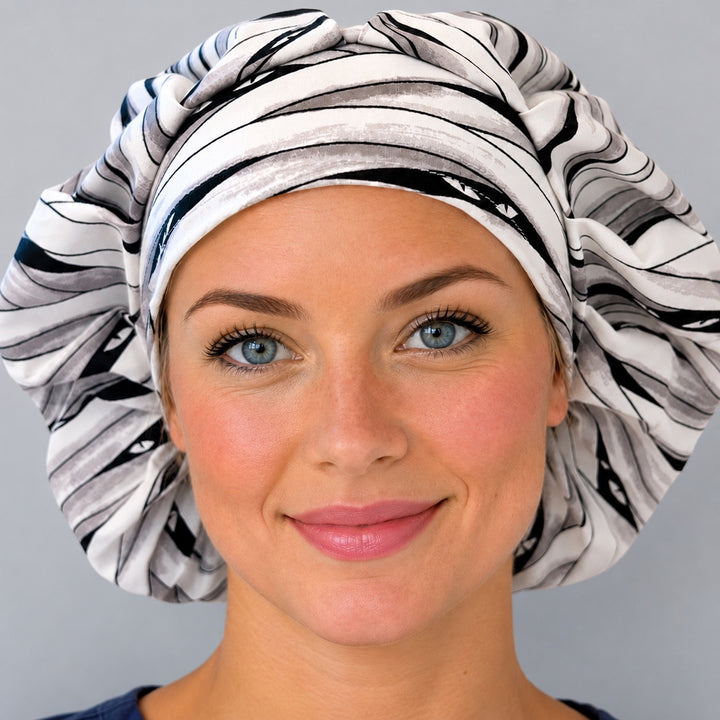 Halloween mummy bouffant scrub cap for women, front view, white and gray mummy-wrap bandage print with peeking eyes, handmade surgical hat by OR World