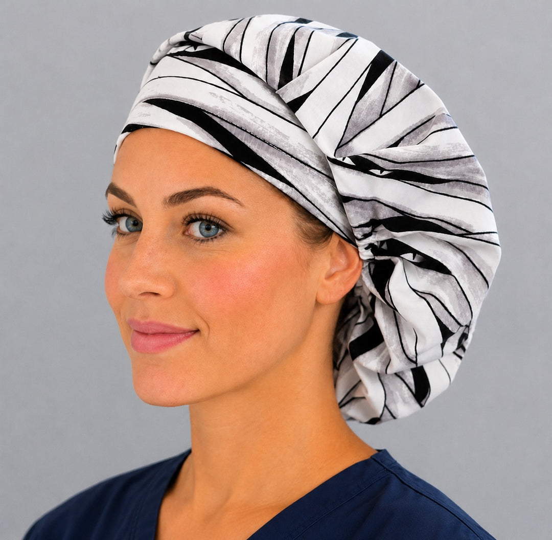 Halloween mummy bouffant scrub cap left three-quarter angle on smiling model showing white and gray mummy bandage wrap with peeking eyes, OR World nurse hat