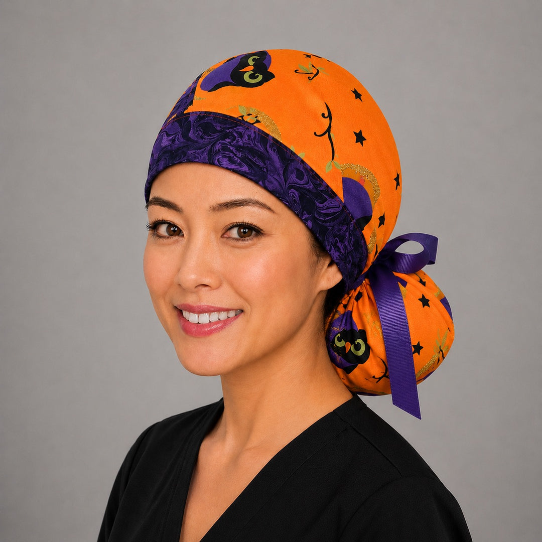 Halloween owl ponytail scrub cap left side profile showing gathered pouch of purple witch owls, moons and stars on orange with purple band and purple ribbon tie