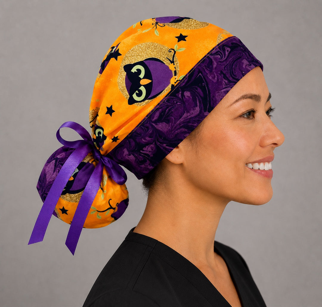 Halloween owl ponytail nurse cap left three-quarter angle on smiling model showing purple witch owls, moons and stars on orange with purple band and purple ribbon bow