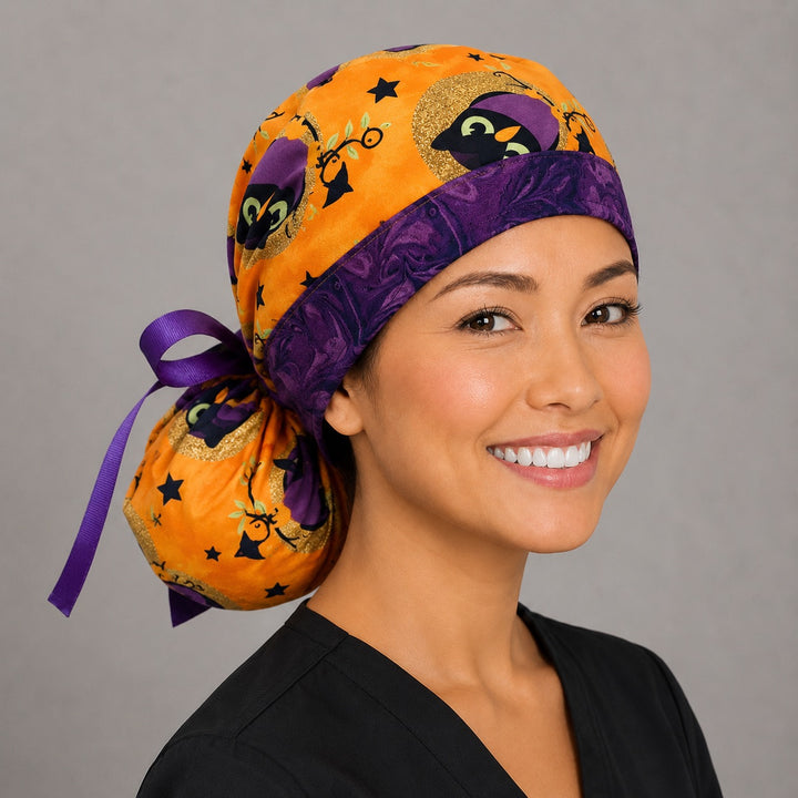 Halloween owl ponytail scrub cap right side profile with full ponytail pouch of purple witch owls and gold moons on orange and long purple ribbon ties