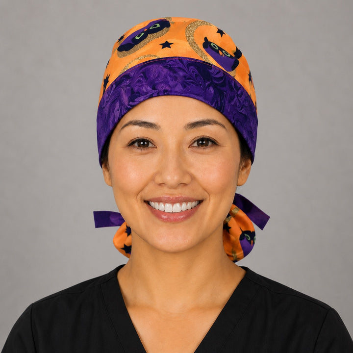 Halloween owl ponytail surgical cap right three-quarter angle showing gathered ponytail pouch of purple witch owls, moons and stars on orange with purple ribbon bow
