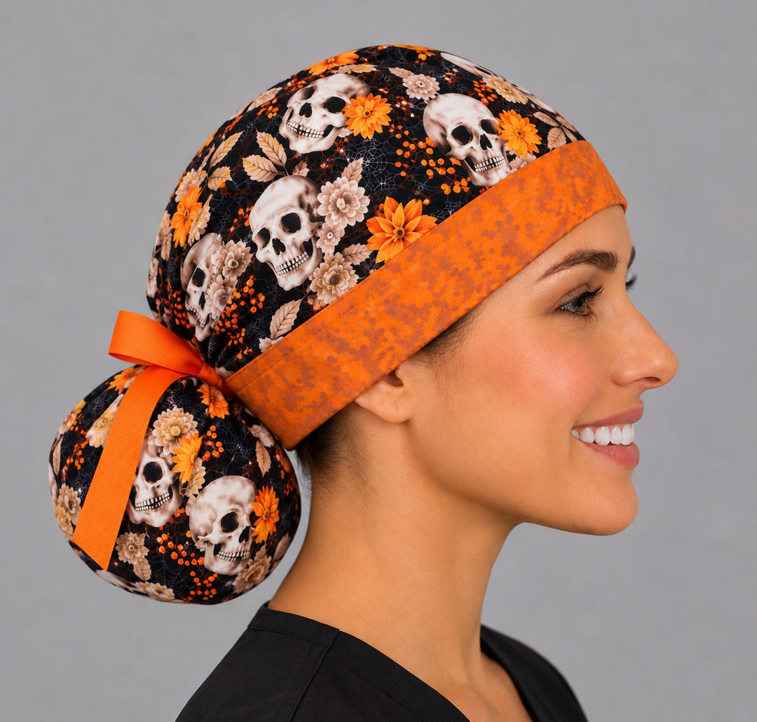 Side profile of a Halloween skull ponytail surgical hat, showing the full round bun pouch at the nape tied with a short orange ribbon