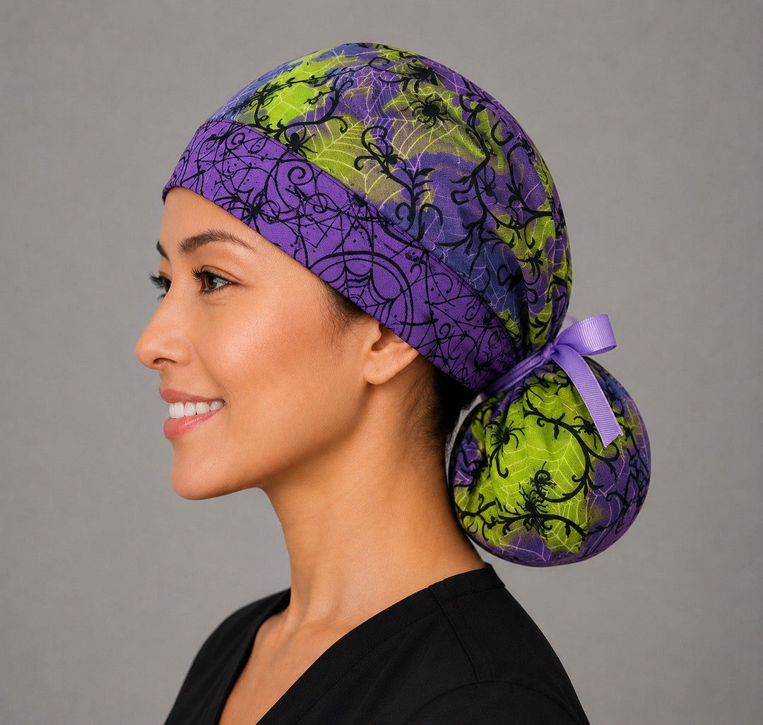 Halloween spider ponytail surgical cap left three-quarter angle on smiling model showing black spiders and webs on purple and lime green with purple ribbon bow