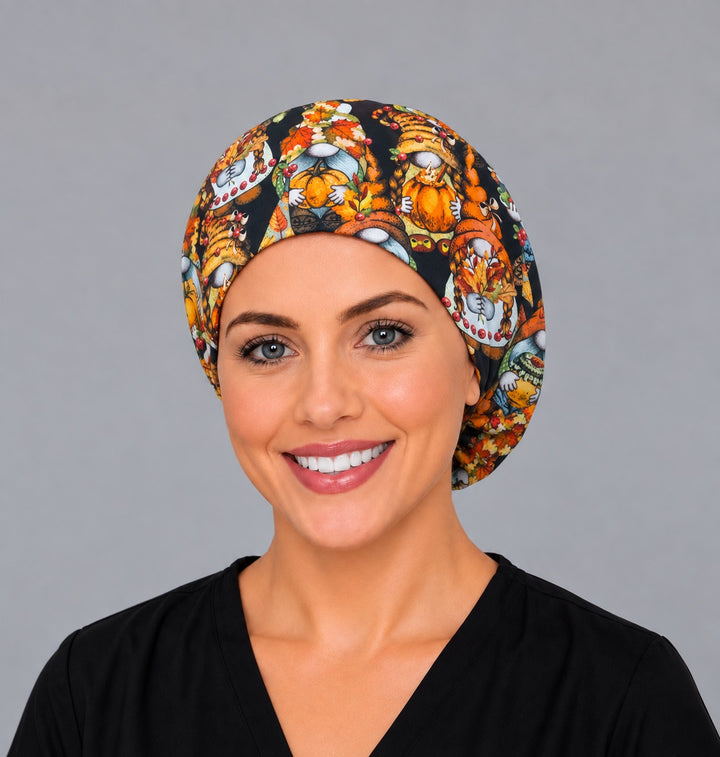 Woman wearing a harvest gnome Euro scrub cap, front view — pumpkin and pie gnomes on black, adjustable fall surgical hat