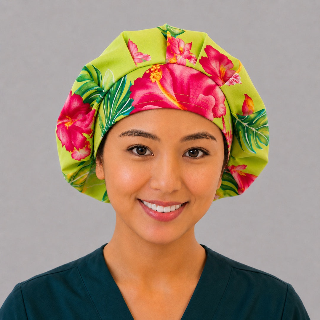 Hawaiian hibiscus bouffant scrub cap left three-quarter angle on smiling model showing pink and orange hibiscus and monstera on lime green, women&