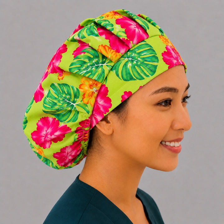 Hawaiian hibiscus bouffant scrub cap right three-quarter angle on smiling model showing pink hibiscus and monstera leaves on lime green, OR World tropical nurse hat