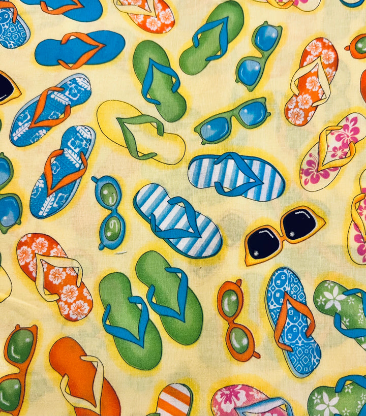 Close detail of Hawaiian Soles flip flop fabric with sunglasses and hibiscus sandals on butter yellow cotton